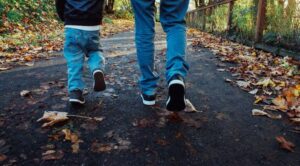 Photo d'un papa et son fils en train de marcher sur une route 