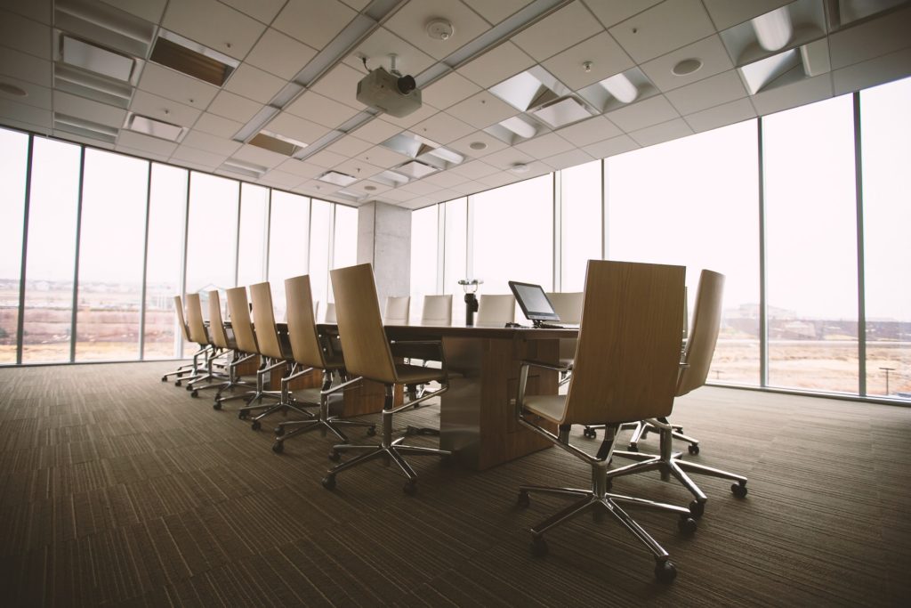 Grande salle de réunion avec une grande table en bois au milieu bordée de grandes vitres