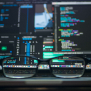 Un zoom photo sur des lunettes posées sur le clavier d'un développeur avec des lignes de codes en fond d'écran
