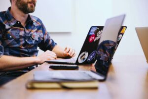 Un homme assied à côté d'un bureau avec son ordinateur portable ouvert devant lui